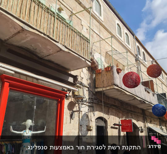 אדם מטפס על קיר בניין עם ציוד טיפוס
